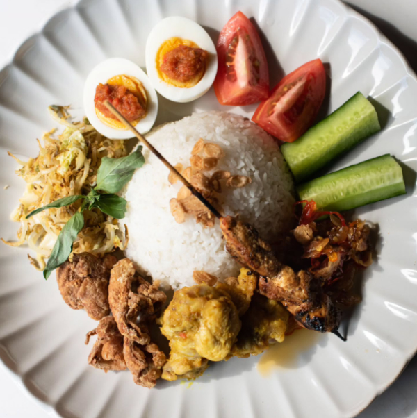 Indonesian rice plate with egg, cucumber, tomato, and side dishes